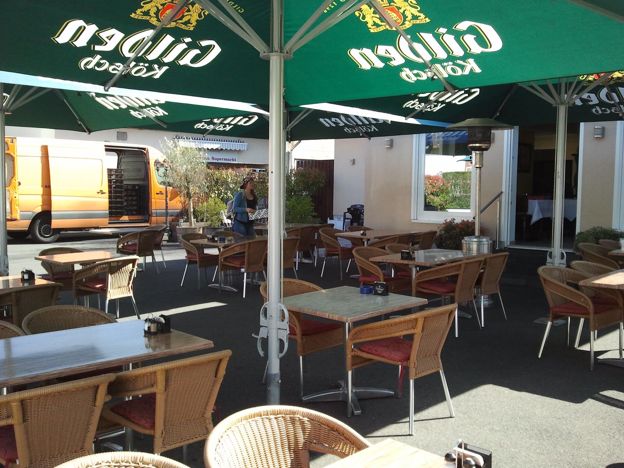 Sonnige Terrasse der Taverne Mythos mit Gilden-Kölsch-Sonnenschirmen